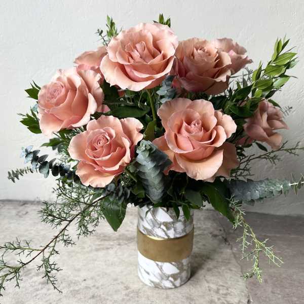 Pink roses arranged in a marble-pattern vase with greenery