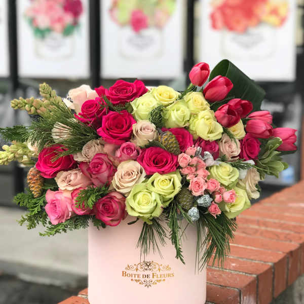 Mixed roses and tulips arranged in a pink hatbox