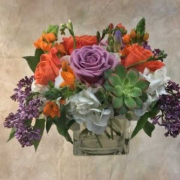 Mixed bouquet with roses, hydrangeas, and succulents in a clear vase