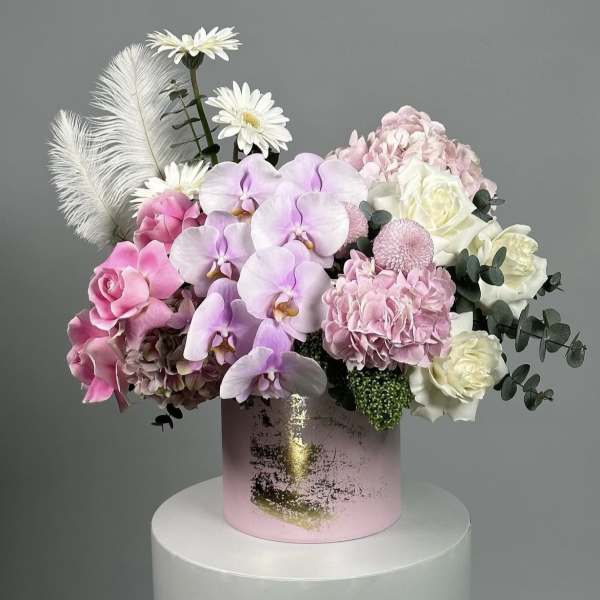 Pink and white floral arrangement in a pink cylindrical box