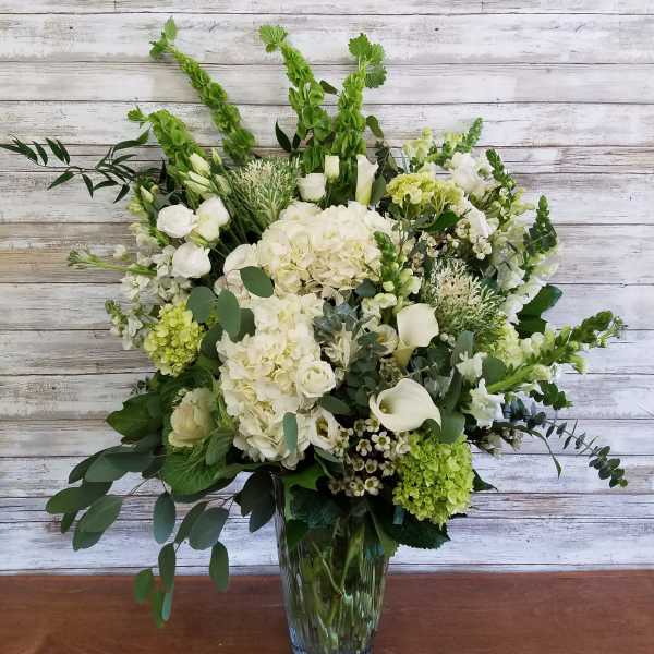 White and green floral arrangement in a clear glass vase