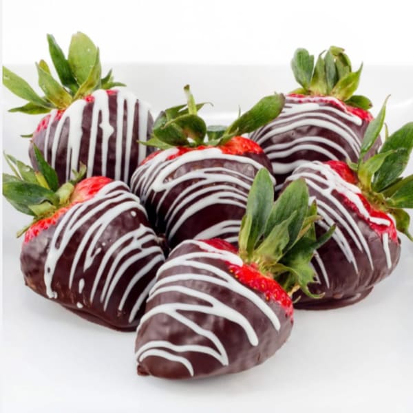 Chocolate-covered strawberries with white drizzle on a white surface