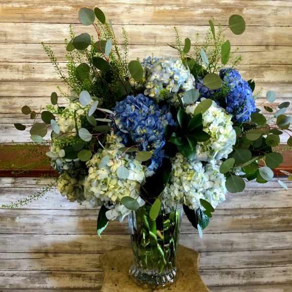 Blue and white hydrangea arrangement in a clear glass vase