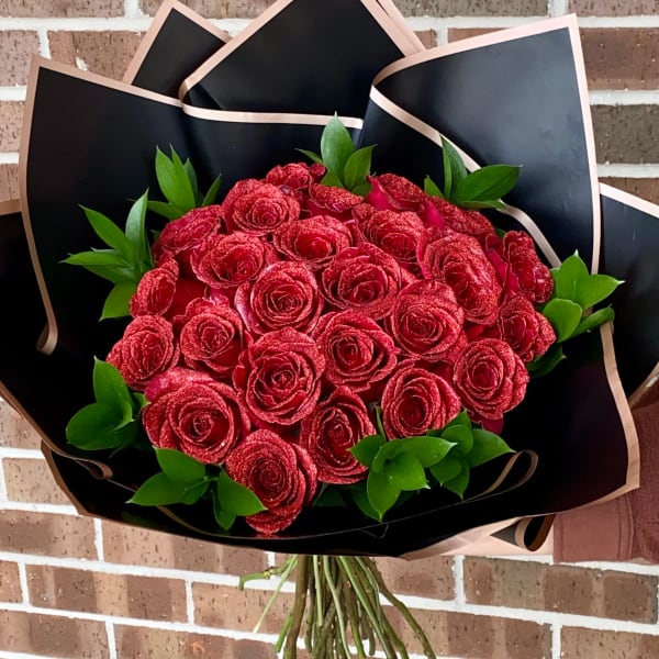 Bouquet of red roses wrapped in black paper with green foliage