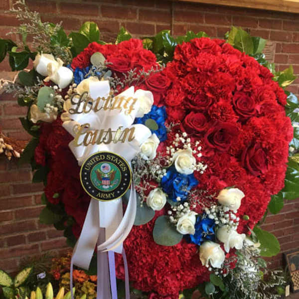 Large red floral standing spray with white and blue accents and a ribbon