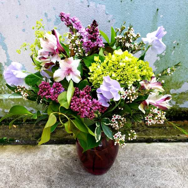 Mixed bouquet in a dark glass vase with pink, purple, and white blooms