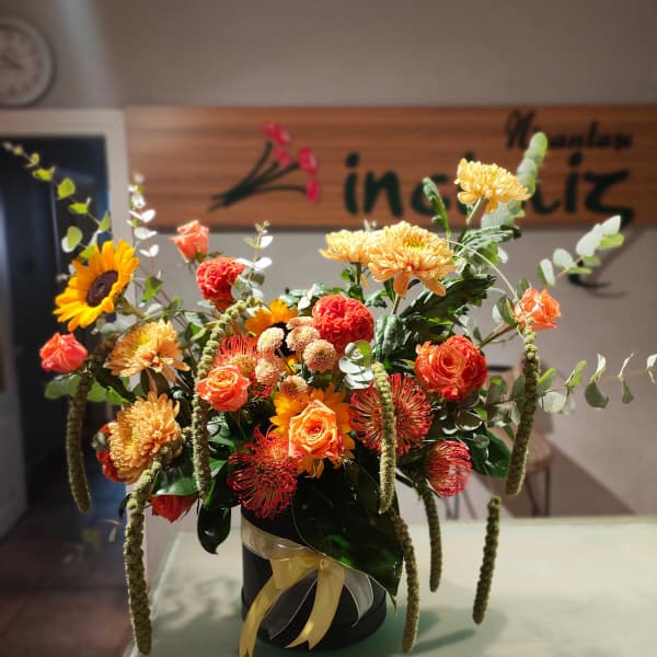 Orange and yellow mixed flower arrangement in a black container