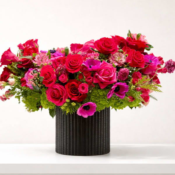 Bright pink and red flower arrangement in a black vase