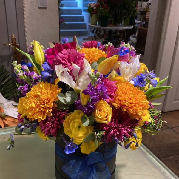 Colorful mixed bouquet in a black hatbox with a blue ribbon