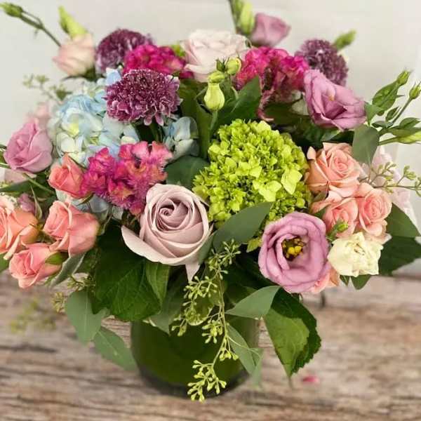 Mixed bouquet of pink, purple, blue, and green flowers in a vase