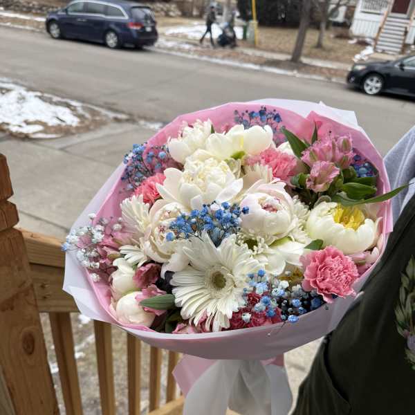 Pink and white mixed bouquet with blue filler flowers wrapped in pink paper
