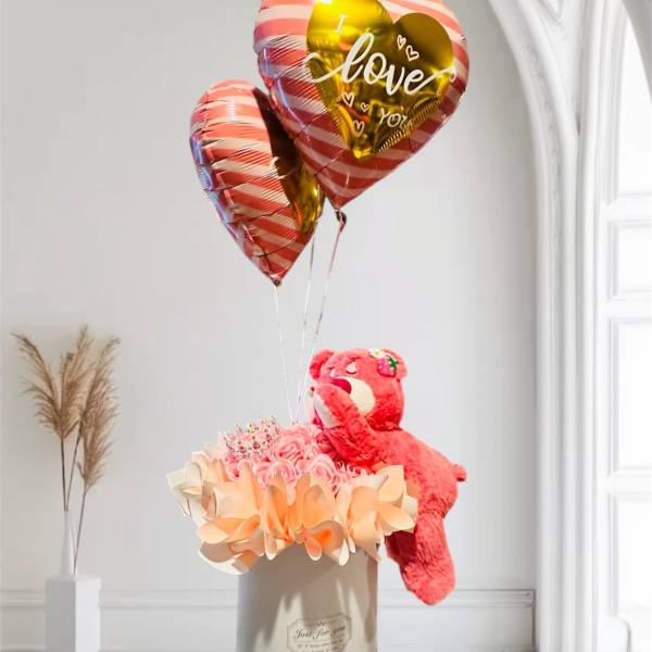 Pink heart balloons above a teddy bear in a gift box