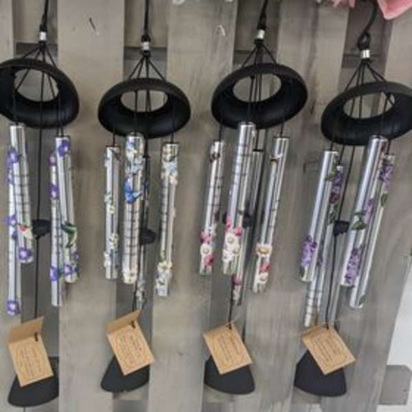 Hanging silver wind chimes with floral accents on a wooden display