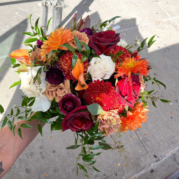 Handheld bouquet of red, orange, white, and purple flowers