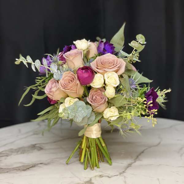 Bouquet of blush and purple roses with eucalyptus on a marble surface