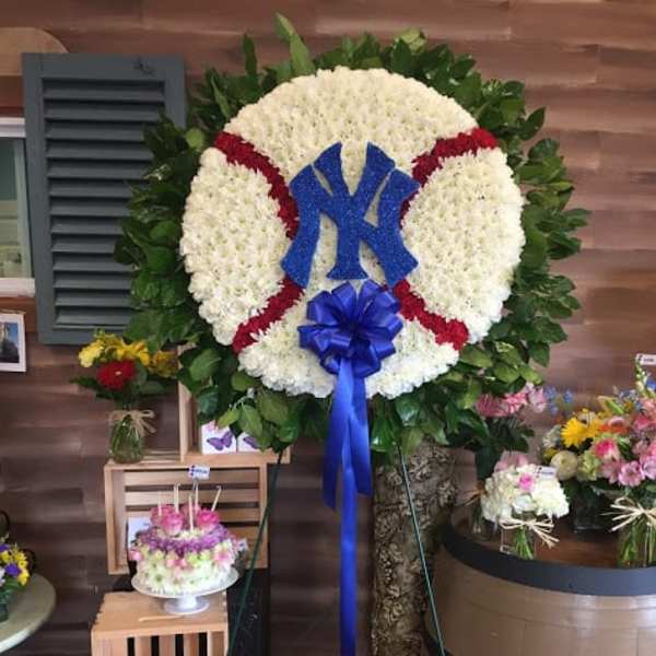Large floral baseball wreath with a blue Yankees logo and ribbon