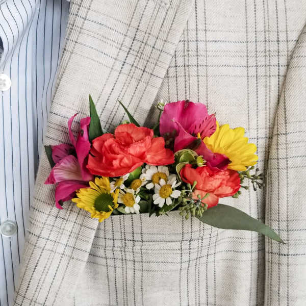 Small bouquet of pink, red, and yellow flowers pinned to a plaid jacket
