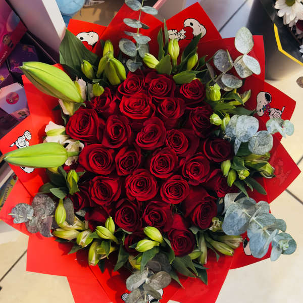 Bouquet of red roses with lily buds wrapped in bright red paper