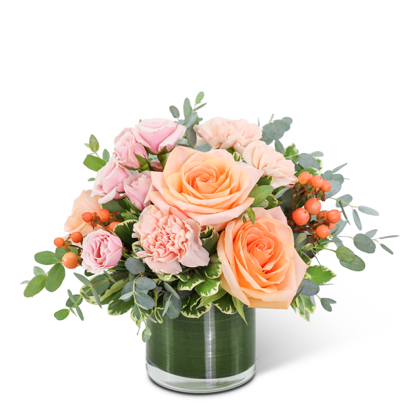 Peach and pink roses with carnations in a glass vase