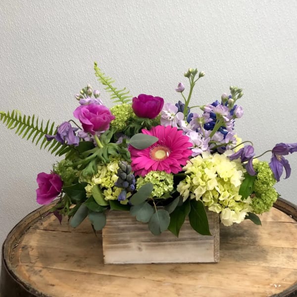 Mixed bouquet with pink and purple flowers in a wooden box