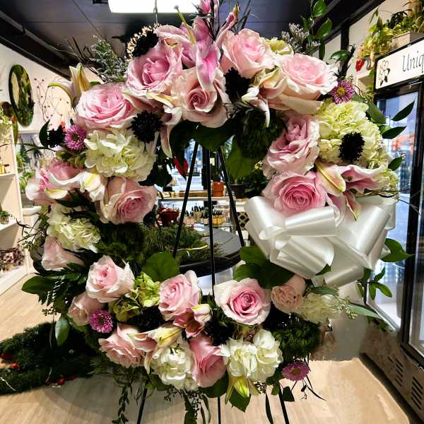 Large pink and white floral standing wreath on an easel with a white bow