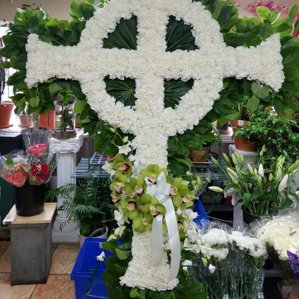 Large white floral cross with green leaves and orchids