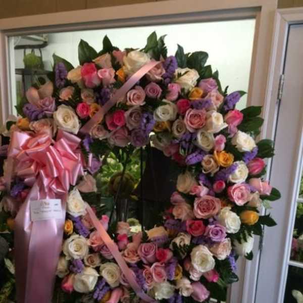 Large floral wreath of pink, white, and purple roses with a pink ribbon