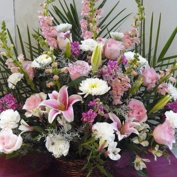 Pink and white floral arrangement with lilies, roses, and carnations in a basket