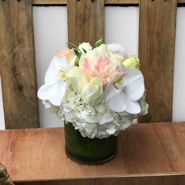 White hydrangea and pale roses in a green glass vase