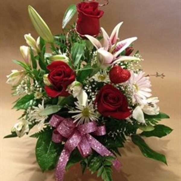 Red roses and white lilies arranged with a pink ribbon bow