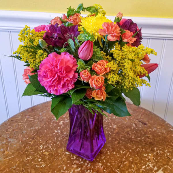 Colorful mixed bouquet in a purple glass vase