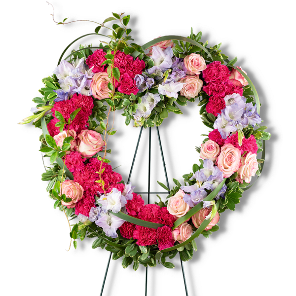 Heart-shaped floral wreath with pink roses and carnations on a stand