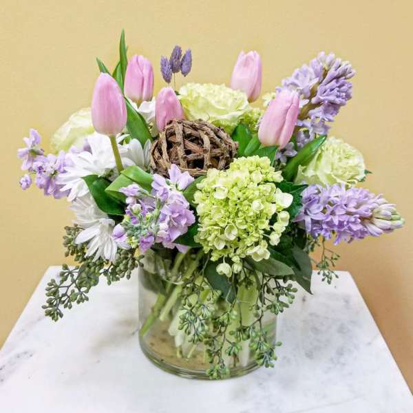 Pink tulips and lavender flowers arranged in a glass vase