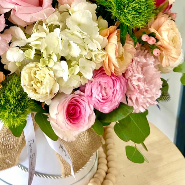 Pink and cream bouquet with roses, hydrangea, and carnations in a wrapped container