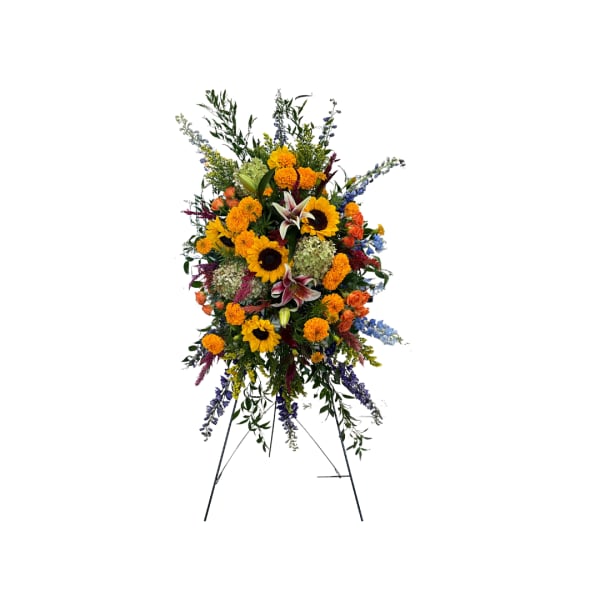Standing floral spray with sunflowers, lilies, and orange blooms on an easel