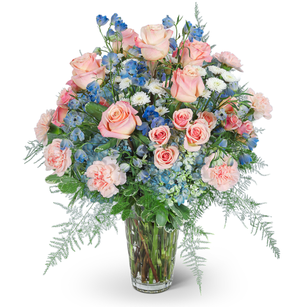 Pink roses, blue flowers, and white blooms in a clear glass vase