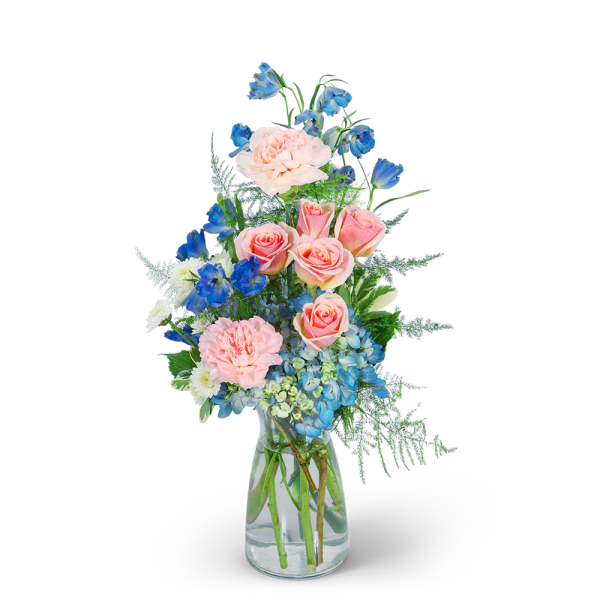 Pink roses and blue flowers arranged in a clear glass vase