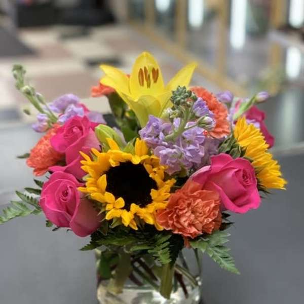 Bright mixed bouquet in a clear glass vase with sunflowers and pink roses