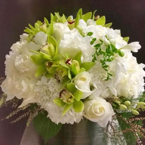 White and green floral arrangement in a dark vase