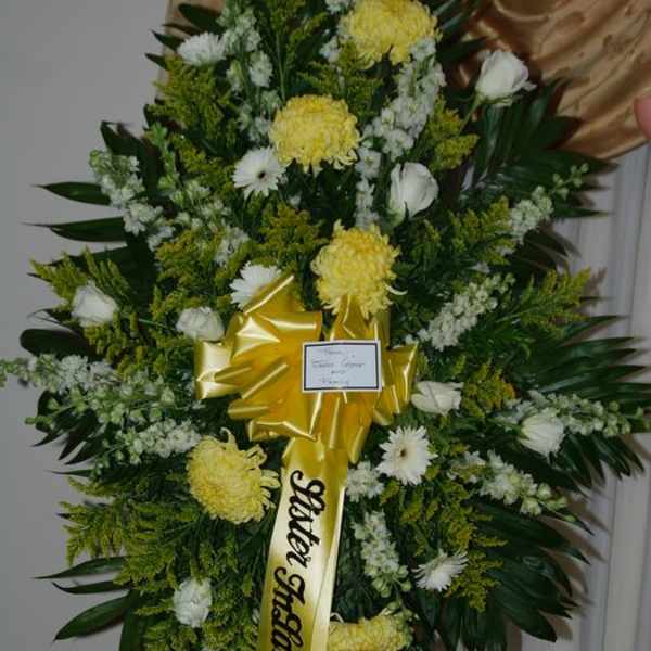 Large funeral wreath with yellow and white flowers on a stand