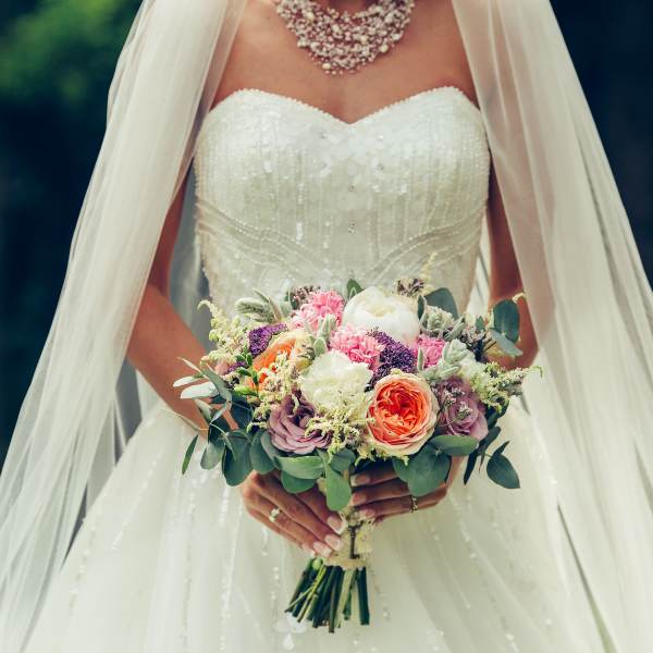 Bride holding a colorful bouquet of roses and mixed flowers