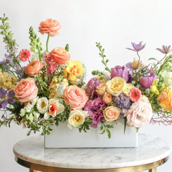 Mixed pastel flower arrangement in a white rectangular vase