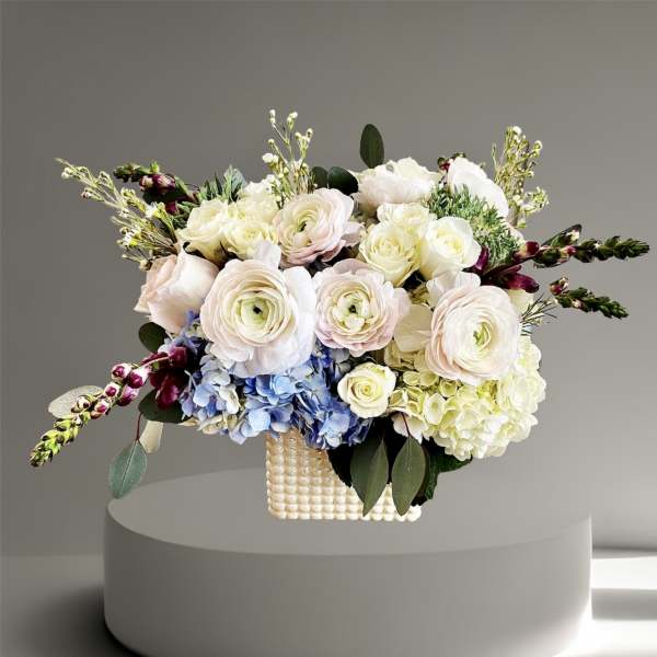 Pastel floral arrangement in a textured square vase