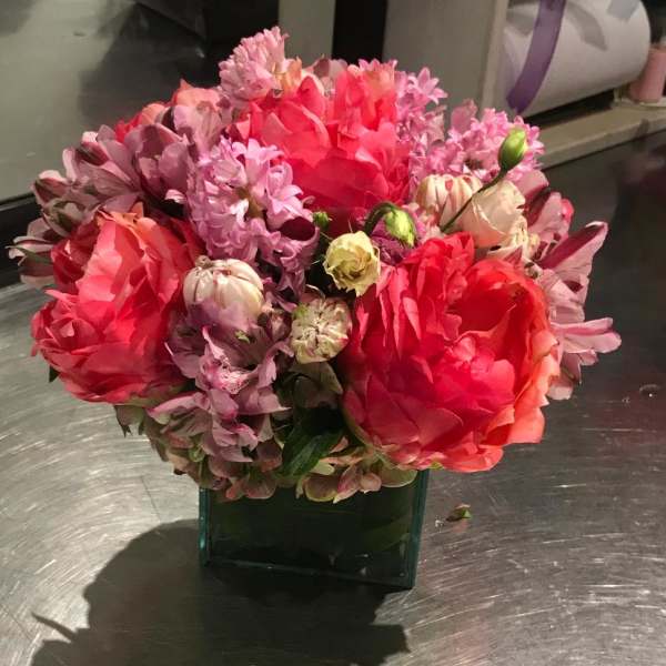 Pink and red mixed bouquet in a square glass vase