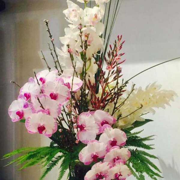 Tall orchid arrangement in a dark vase with pink and white blooms