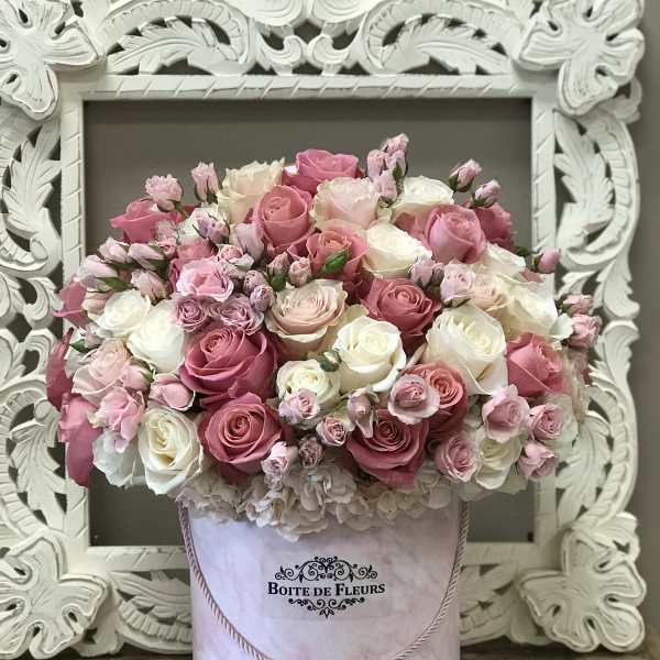 Pink and white rose arrangement in a round hatbox