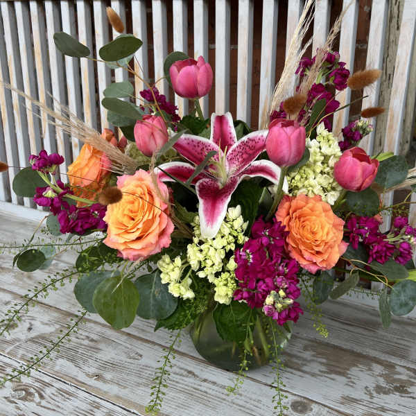 Bouquet of pink lilies, roses, and tulips in a glass vase