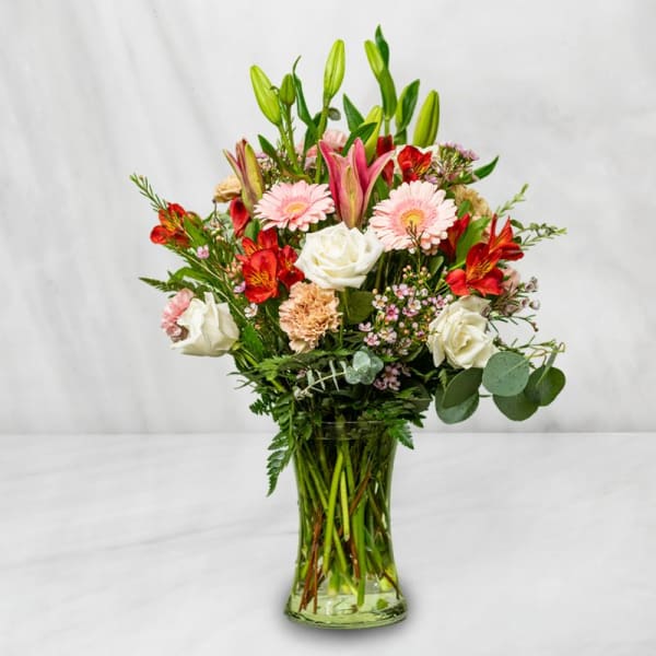 Mixed bouquet of lilies, roses, gerbera daisies, and alstroemeria in a glass vase