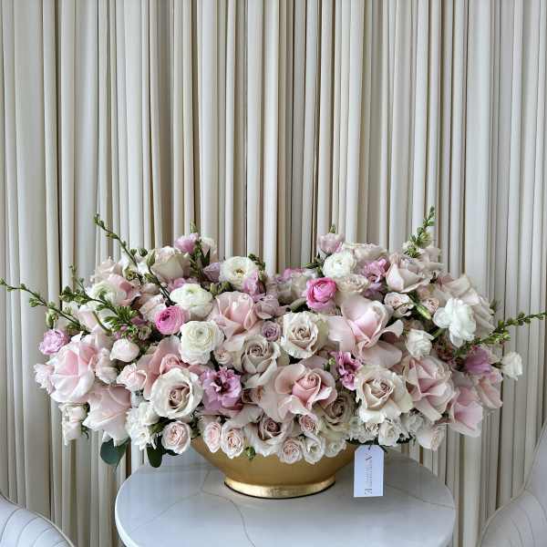 Large pastel pink and white floral arrangement in a gold bowl.