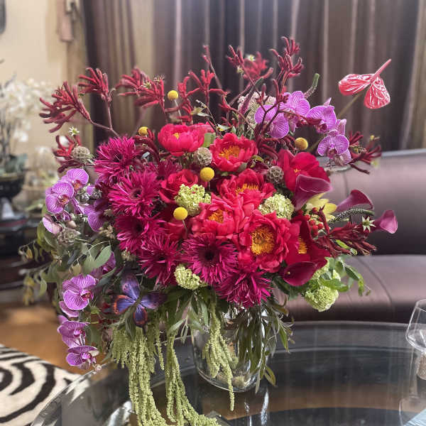 Bright pink floral arrangement in a clear glass vase with orchids and calla lilies